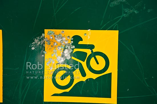 Vandalism damage to a Department of Conservation DOC trail bike riding sign by shotgun pellets blast, New Zealand (NZ)