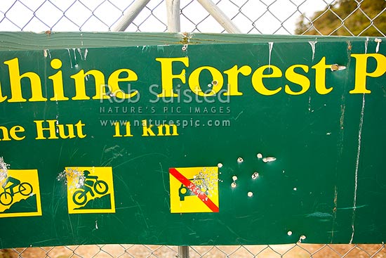 Vandalism damage to a Department of Conservation DOC sign by rifle bullet and shotgun pellets holes, New Zealand (NZ)