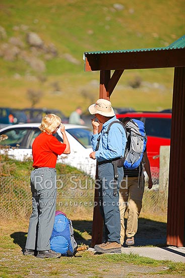 Walkers applying sunscreen before heading off on day walk in the Matukituki Valley West Branch. Mt Aspiring National Park, Wanaka, Queenstown Lakes District, Otago Region, New Zealand (NZ)