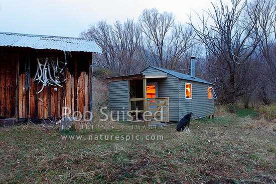 Lake McRae huts (old and new) in early morning - light with candle light on a moody autumn morning, Molesworth Station, Marlborough District, Marlborough Region, New Zealand (NZ)