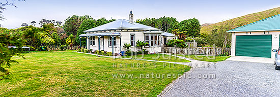 Old neatly kept farmhouse, garage and lawn, with childrens toys about. Panorama, New Zealand (NZ)