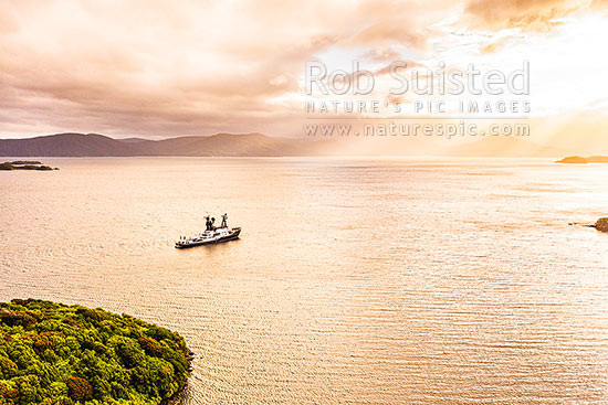 Yacht MY Arctic at anchor in Paterson Inlet, with evening glowing skies, Rakiura. Aerial view, Paterson Inlet, Stewart Island District, Southland Region, New Zealand (NZ)