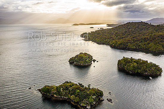 Faith, Hope and Charity Group of islands in Paterson Inlet Whaka a Te Wera. Glowing evening skies of Rakiura beyond. Aerial view, Paterson Inlet, Stewart Island District, Southland Region, New Zealand (NZ)