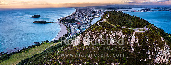 Mt Maunganui summit Mauao at the Tauranga Harbour Entrance. 231m high lava dome. Mt Maunganui Beach left, Tauranga Harbour right. Aerial panorama at dusk, Mount Maunganui, Tauranga District, Bay of Plenty Region, New Zealand (NZ)