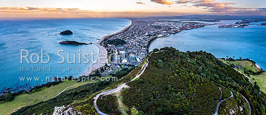 Mt Maunganui summit Mauao at the Tauranga Harbour Entrance. 231m high lava dome. Mt Maunganui Beach left, Tauranga Harbour right. Aerial view at dusk, Mount Maunganui, Tauranga District, Bay of Plenty Region, New Zealand (NZ)