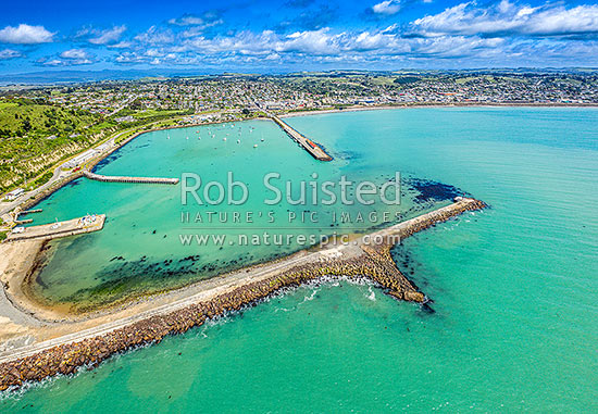 Oamaru harbour breakwater and Holmes Wharf (centre) enclosing Friendly Bay at left. Aerial view towards Oamaru town, Oamaru, Waitaki District, Canterbury Region, New Zealand (NZ)