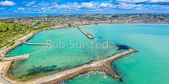 Oamaru harbour breakwater and Holmes Wharf (centre) enclosing Friendly Bay at left. Panorana aerial view towards Oamaru town, Oamaru, Waitaki District, Canterbury Region, New Zealand (NZ)