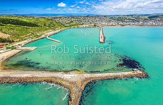 Oamaru harbour breakwater and Holmes Wharf enclosing Friendly Bay centre. Aerial view towards Oamaru town, Oamaru, Waitaki District, Canterbury Region, New Zealand (NZ)