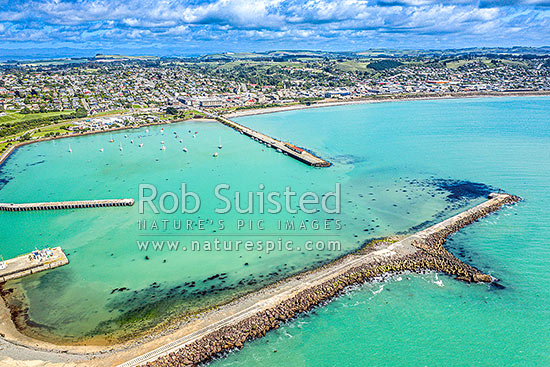 Oamaru harbour breakwater and Holmes Wharf (centre) enclosing Friendly Bay at left. Aerial view towards Oamaru town beyond, Oamaru, Waitaki District, Canterbury Region, New Zealand (NZ)