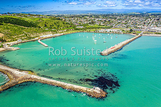 Oamaru harbour breakwater and Holmes Wharf (right) enclosing Friendly Bay centre. Aerial view towards Oamaru town beyond right, Oamaru, Waitaki District, Canterbury Region, New Zealand (NZ)