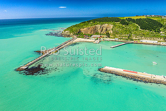 Oamaru harbour breakwater and Holmes Wharf (right) enclosing Friendly Bay, with Oamaru Blue Penguin Colony and Cape Wanbrow beyond. Aerial view, Oamaru, Waitaki District, Canterbury Region, New Zealand (NZ)