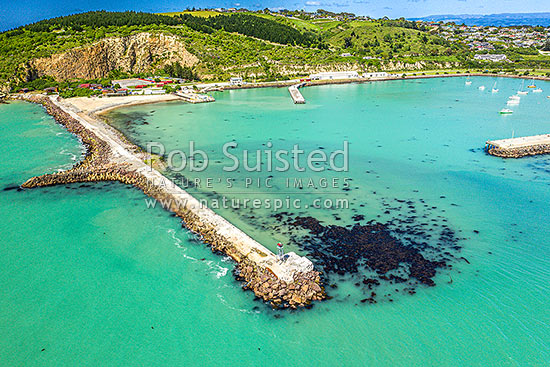 Oamaru harbour breakwater and Holmes Wharf (right) enclosing Friendly Bay, with Oamaru Blue Penguin Colony and Cape Wanbrow beyond at left. Aerial view, Oamaru, Waitaki District, Canterbury Region, New Zealand (NZ)