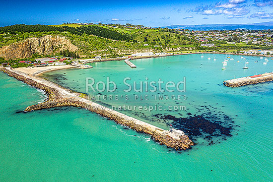 Oamaru harbour breakwater and Holmes Wharf (right) enclosing Friendly Bay, with Oamaru Blue Penguin Colony and Cape Wanbrow beyond at left. Aerial view, Oamaru, Waitaki District, Canterbury Region, New Zealand (NZ)