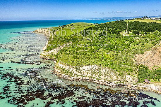 Oamaru coast and Cape Wanbrow, looking south along Otago coast towards Shag Point. WWII coastal defence battery visible centre. Aerial view, Oamaru, Waitaki District, Canterbury Region, New Zealand (NZ)