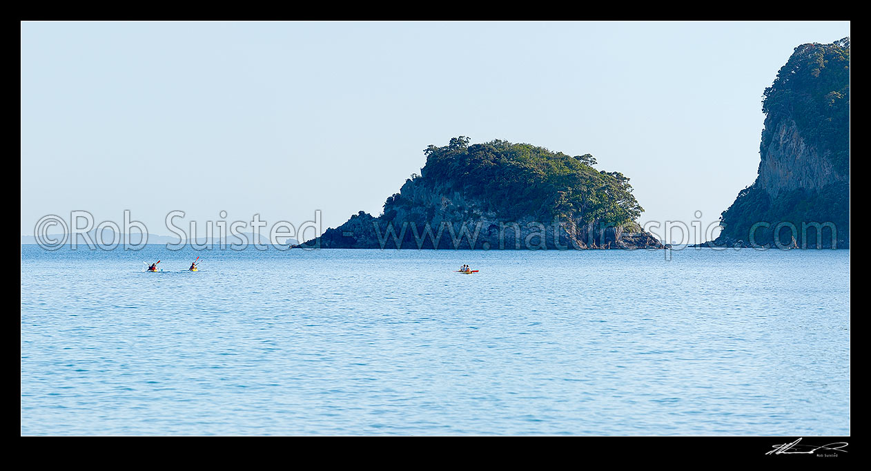 Image of Sea kayakers in Whanganui A Hei Marine Reserve, with Poikeke Island centre and Motueka (Pigeon) Islands right. Cathedral Cove. Panorama, Hahei, Coromandel Peninsula, Thames-Coromandel District, Waikato Region, New Zealand (NZ) stock photo image