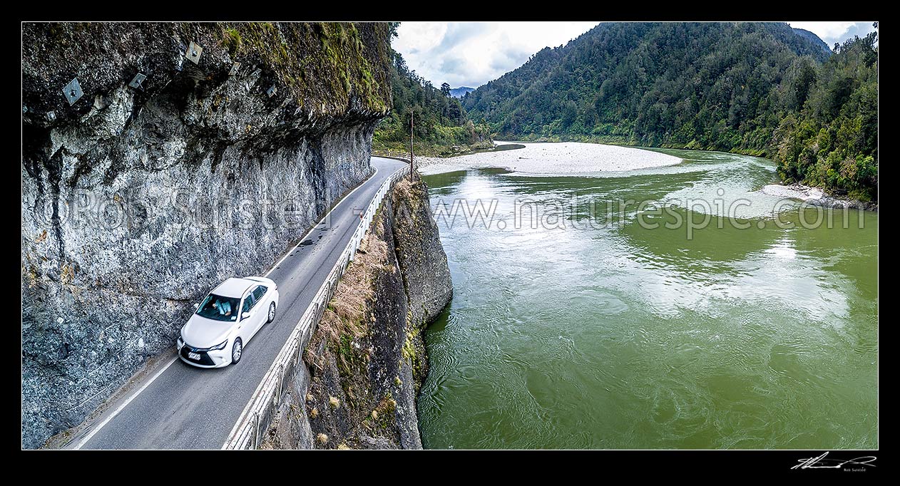 Image of Hawks Crag under cut in the Buller Gorge, beside the Buller River and Dee Point (right). State Highway 6 (SH6). Aerial panorama of car passing underneath this narrow section in Lower Buller Gorge, Westport, Buller District, West Coast Region, New Zealand (NZ) stock photo image