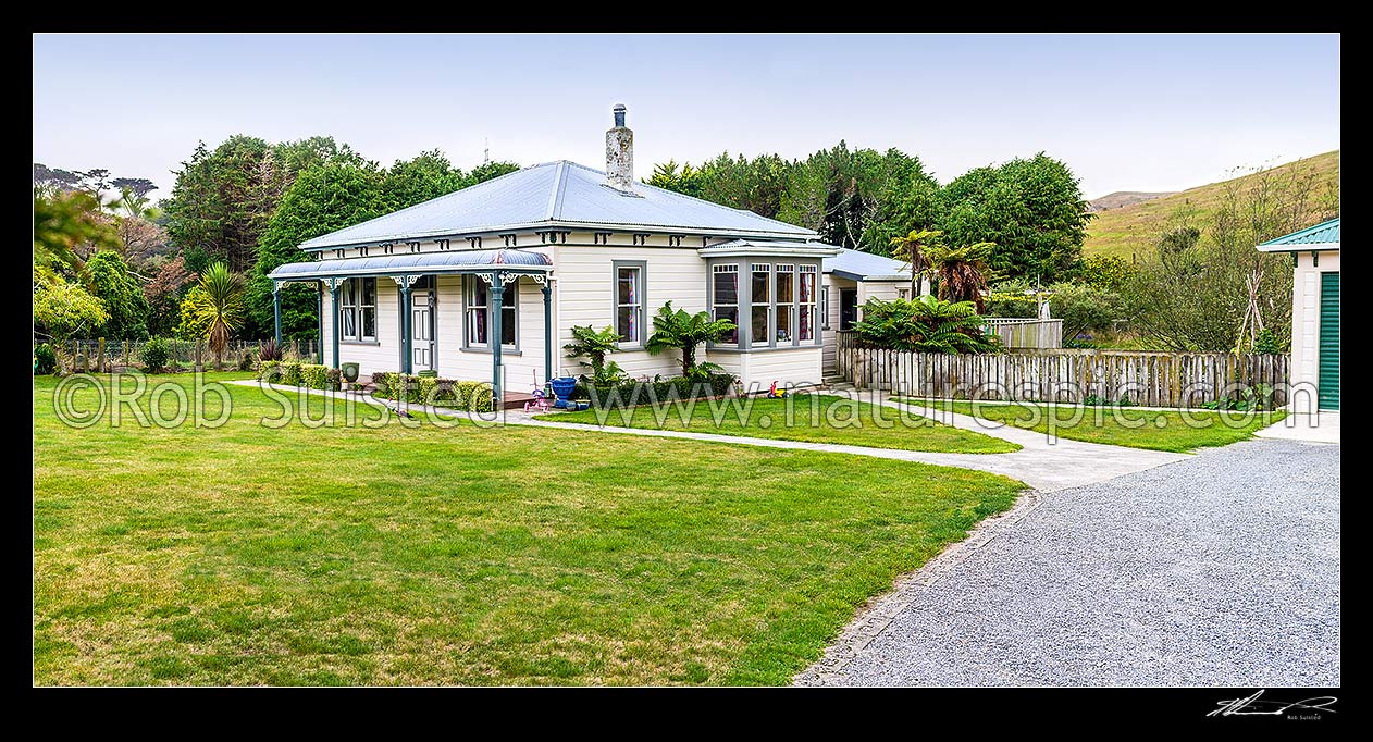 Image of Old neatly kept farmhouse, garage and lawn, with childrens toys about. Panorama, New Zealand (NZ) stock photo image