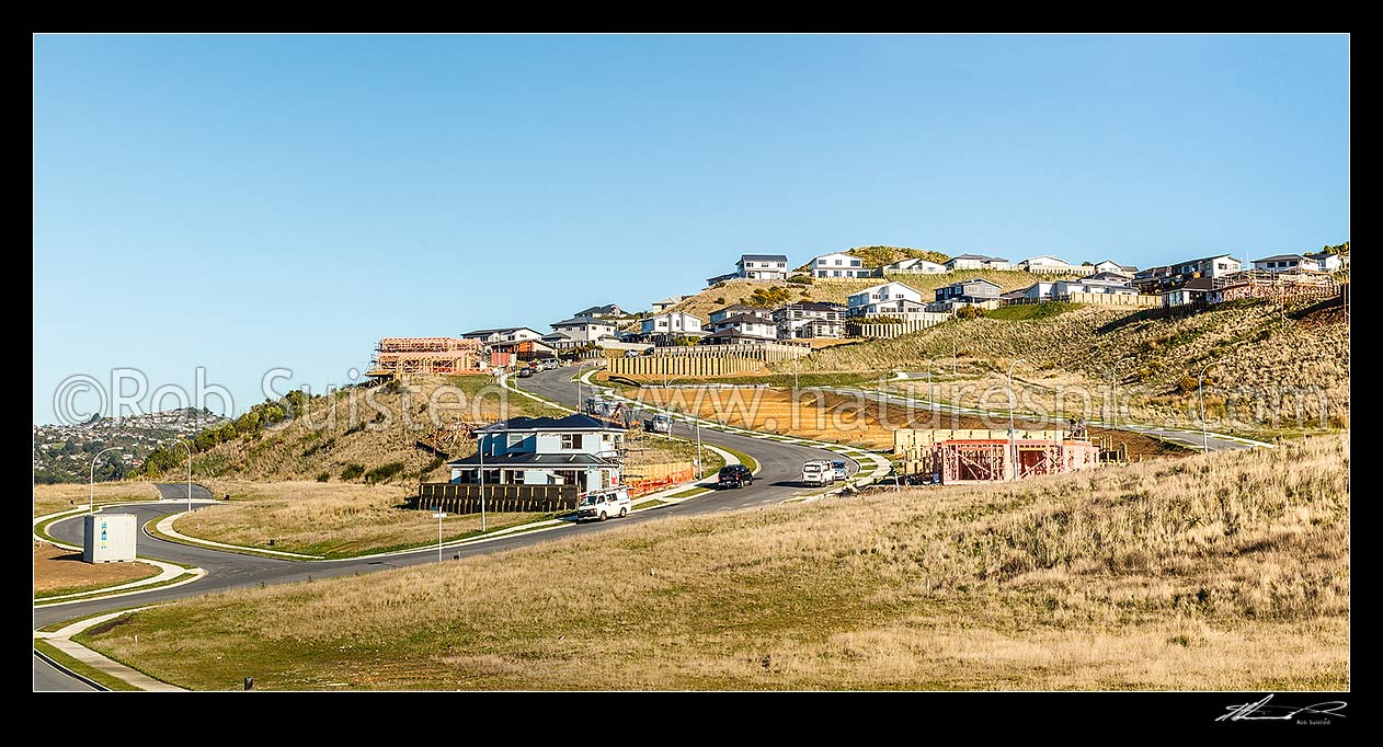 Image of New houses being built in a new suburb. Earthworks and new sections being developed with tradesmen and builders vehicles. New homes above. Panorama, Wellington City District, Wellington Region, New Zealand (NZ) stock photo image