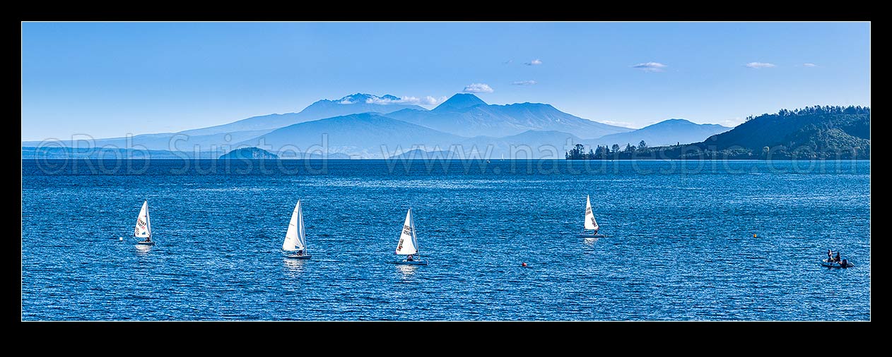 Image of Lake Taupo, looking south to volcanic central plateau, Tongariro National park and Mountains Ruapehu, Ngauruhoe and Tongariro. With small sailboats training in foreground. Panorama, Taupo, New Zealand (NZ) stock photo image